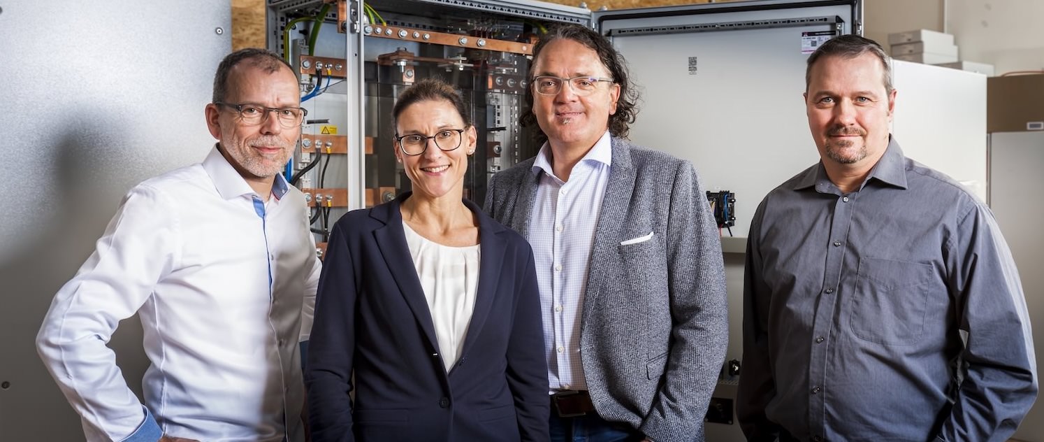 Führungsteam vor Schaltschrank – Experten für industrielle Automatisierung und Elektrotechnik