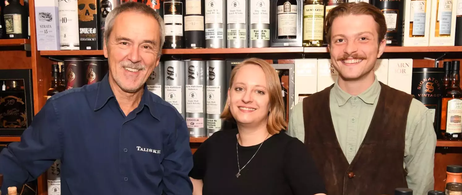 Mitarbeiter in Whisky-Shop vor Regal mit Premium-Whisky
